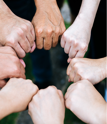 Eight hands are forming a circle with closed fists touching in the center, representing unity and teamwork.