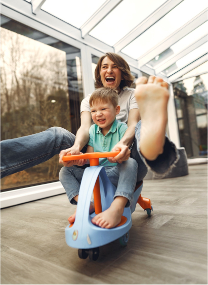 A woman and her son riding on a toy car.