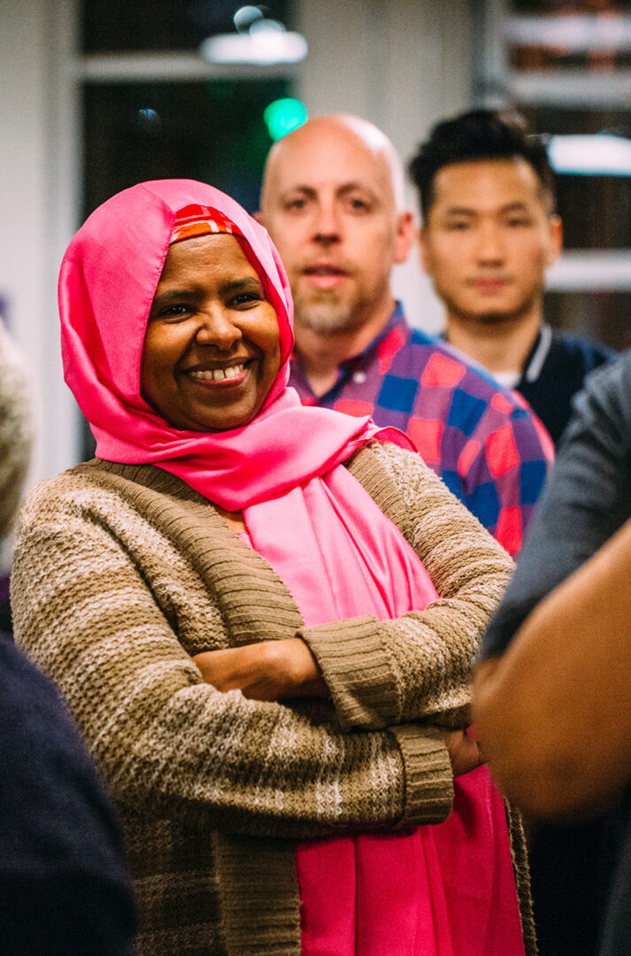 A woman in a pink hijab is standing in front of a group of people.