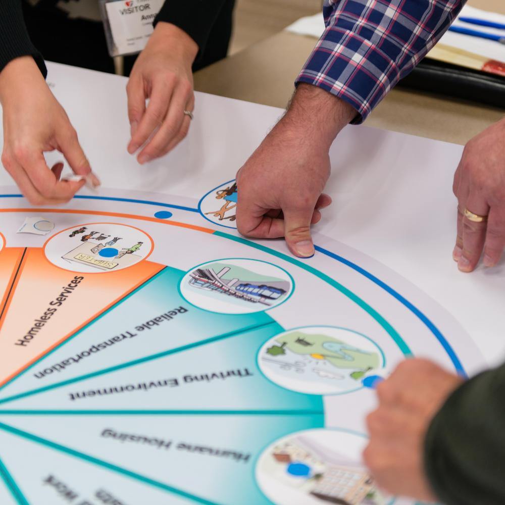 A group of people pointing to a diagram on a table.