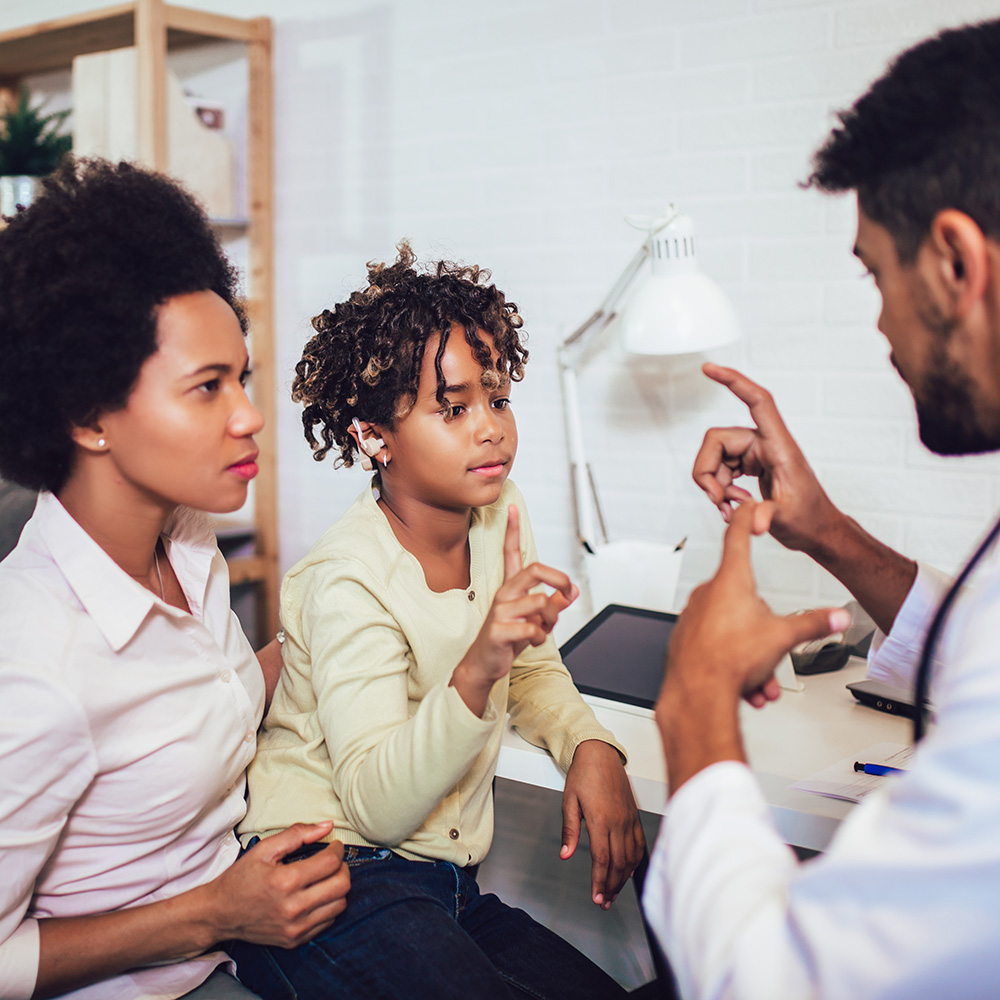 A doctor is talking to a woman and a child in a doctor's office.