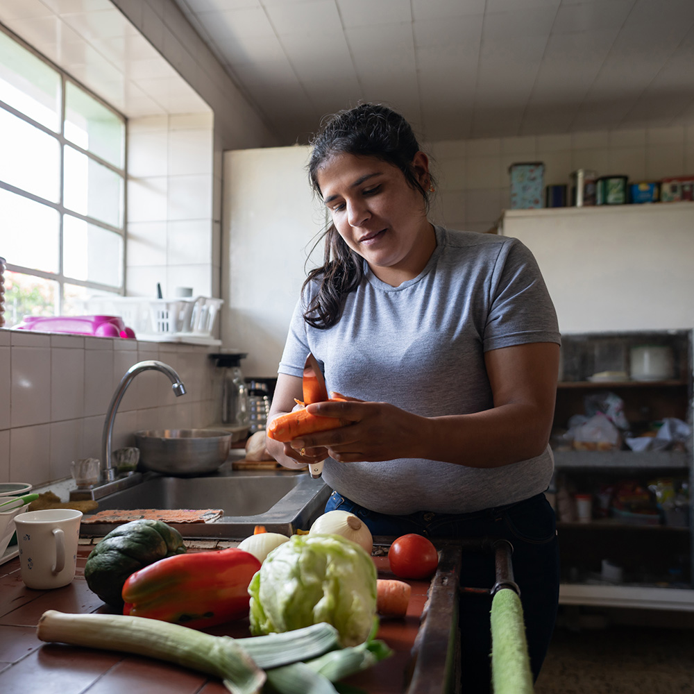 A woman is preparing vegetables in a kitchen.