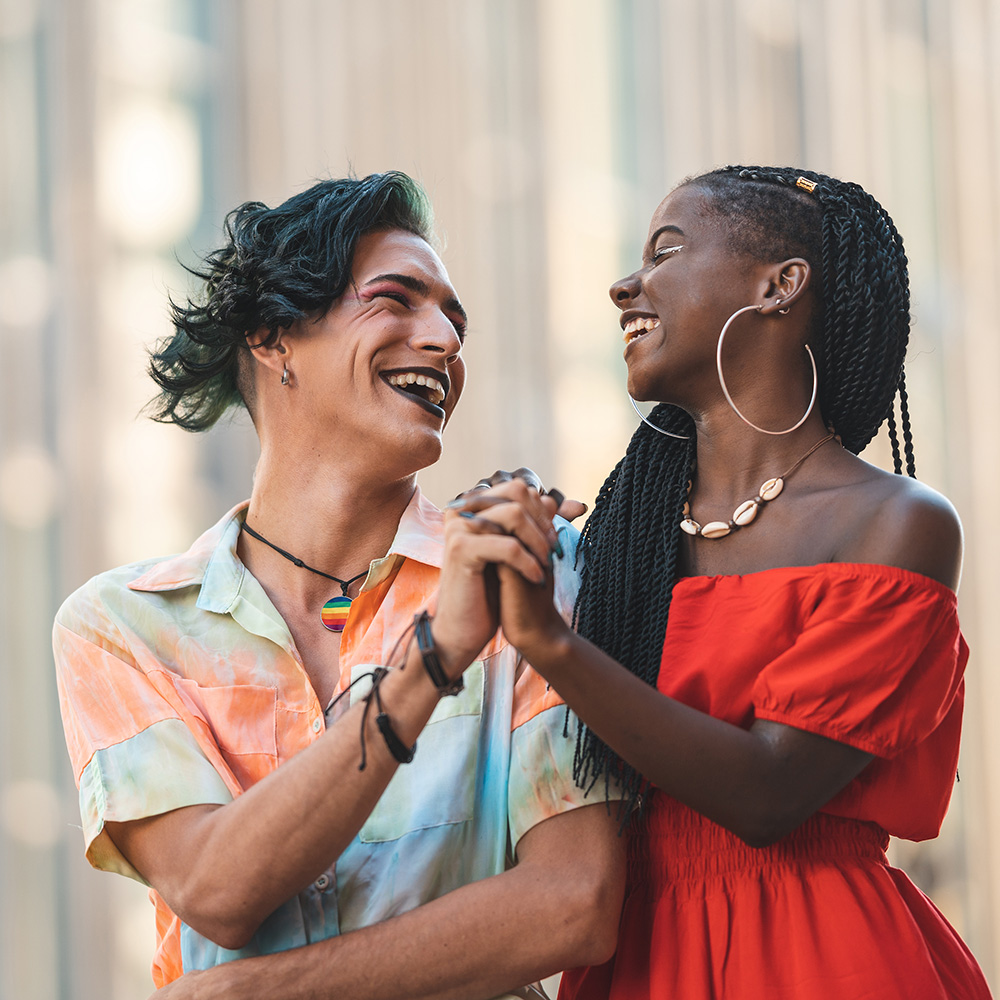 A man and woman are laughing together in a city.