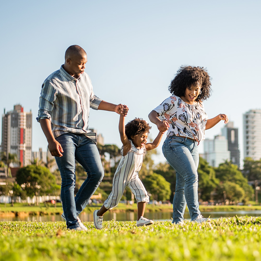 A family is running in a park with a city in the background.