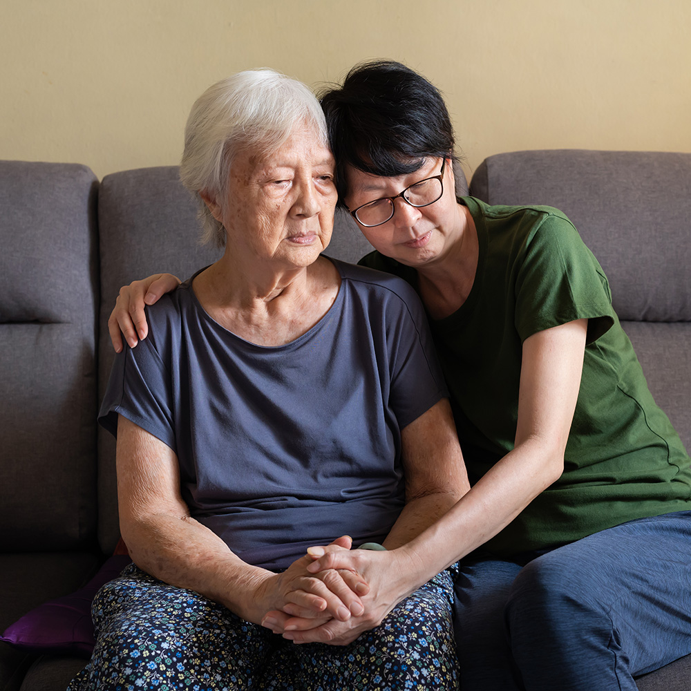 A woman is hugging an older woman on a couch.