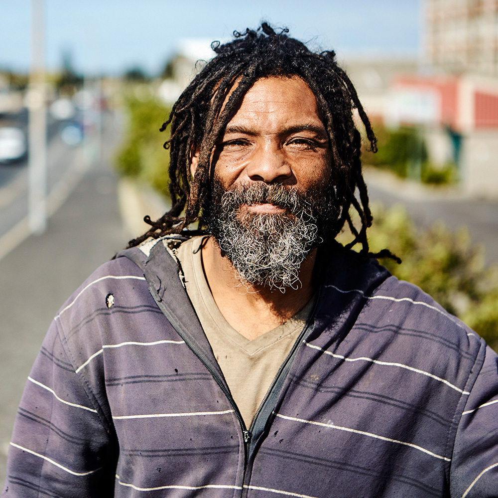 A man with dreadlocks standing on a street.