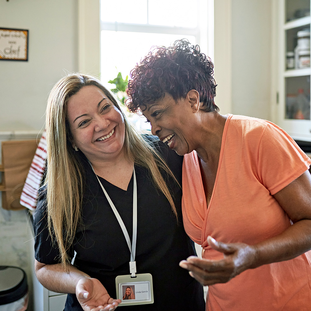 Two women laughing in a kitchen.