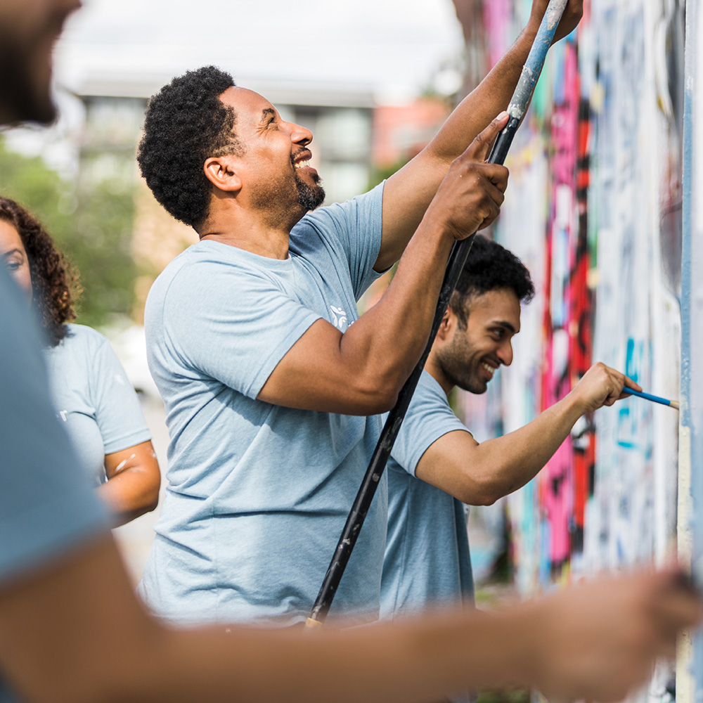 A group of people painting graffiti on a wall.