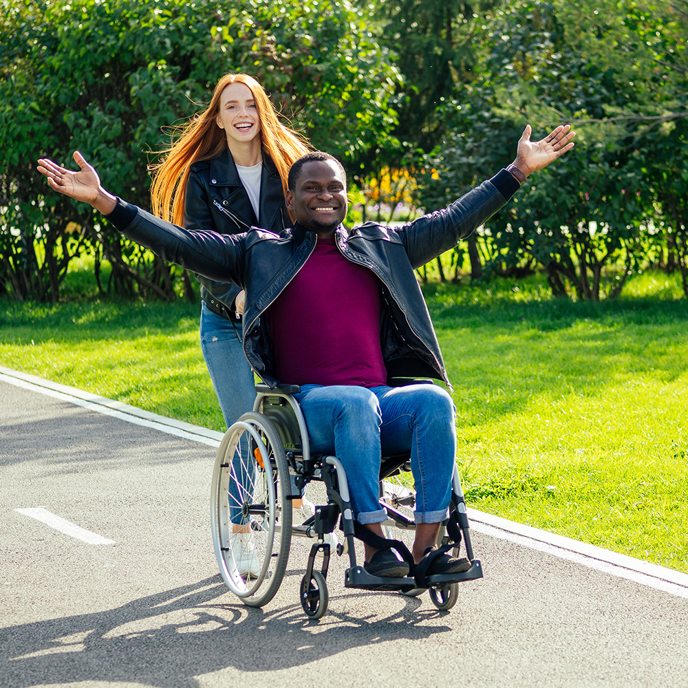 A man in a wheelchair and a woman with her arms outstretched.