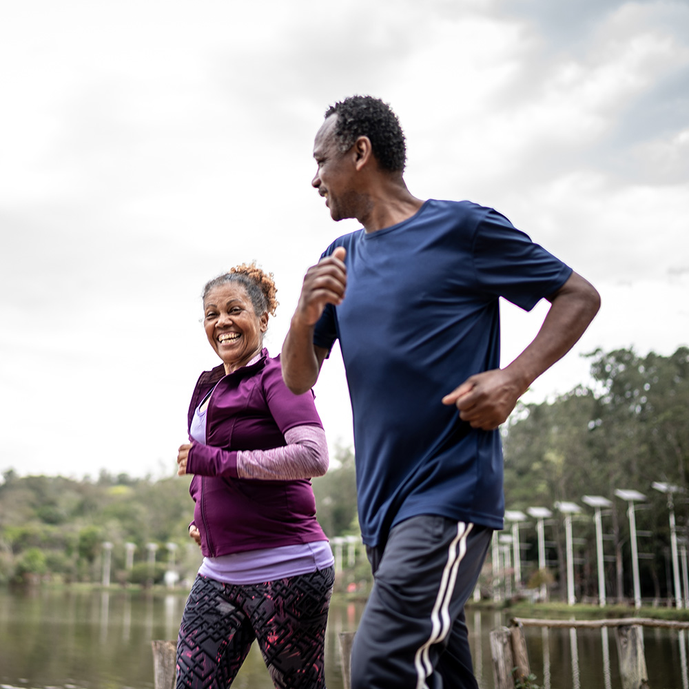 An older couple jogging near a lake.