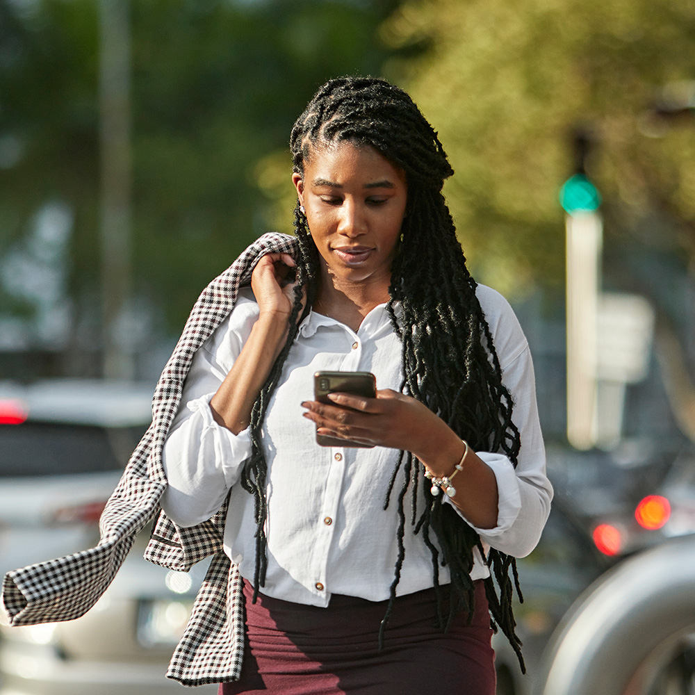 A woman with dreadlocks looking at her phone.