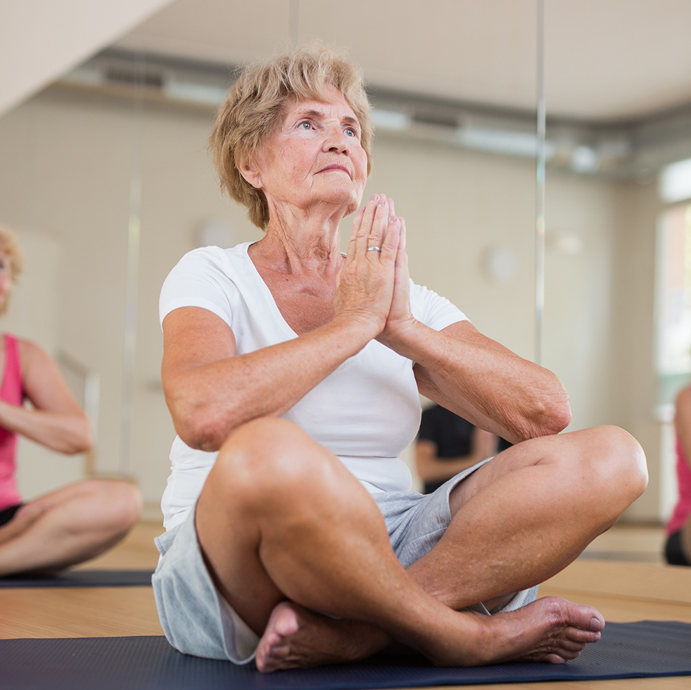 A group of older women doing yoga in a gym.