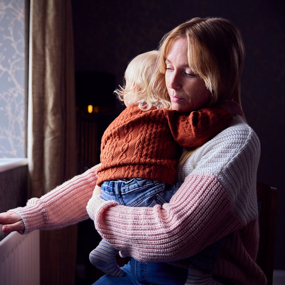 A woman holding a child in front of a window.