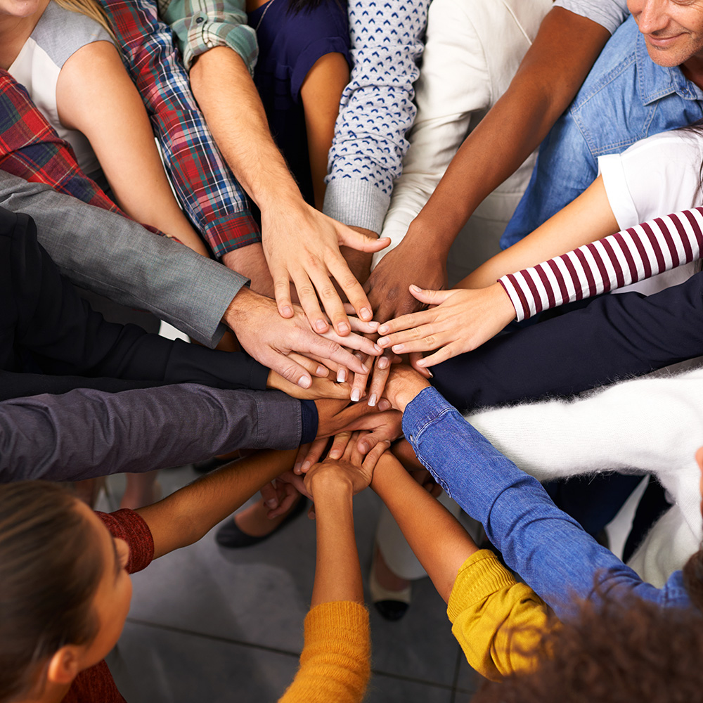 A group of people putting their hands together in a circle.