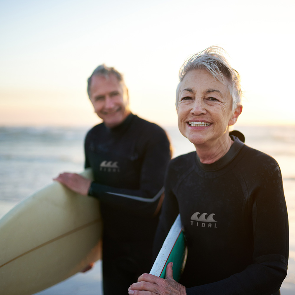 A man and a woman standing on the beach holding surfboards.