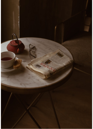 A table with a cup of tea and a newspaper on it.